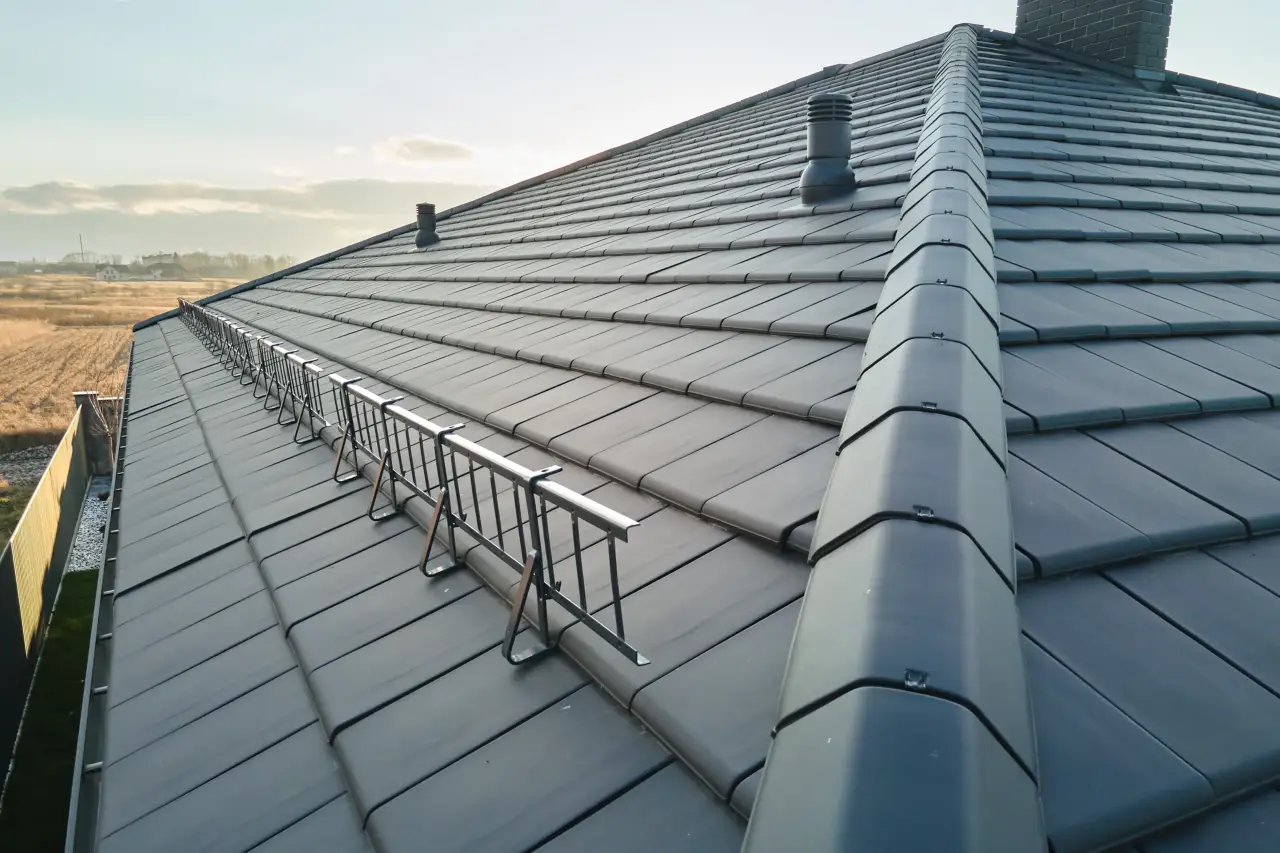 Toiture en tuiles sombres propre avec faîtage et éléments de ventilation